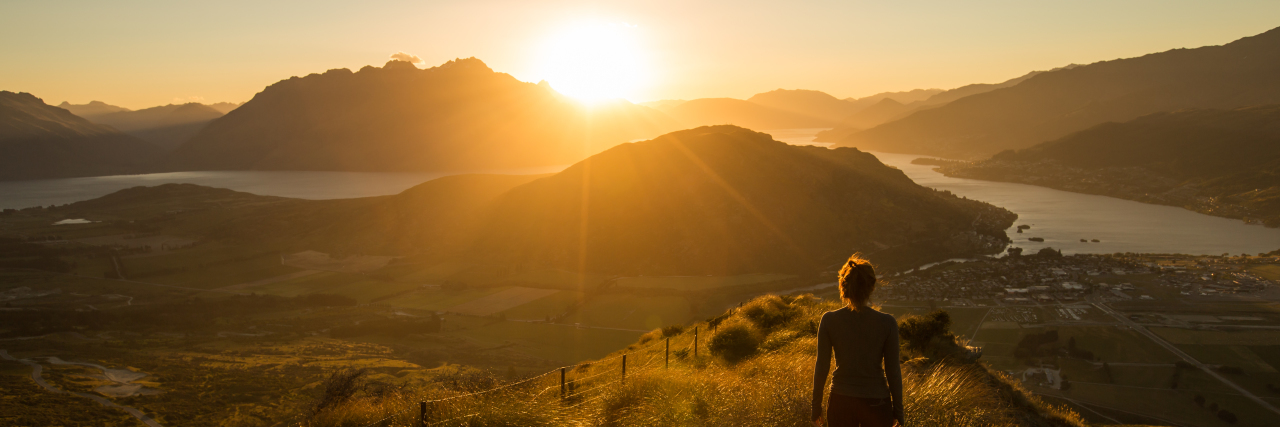 Woman silhouetted at sunset on a mountain.
