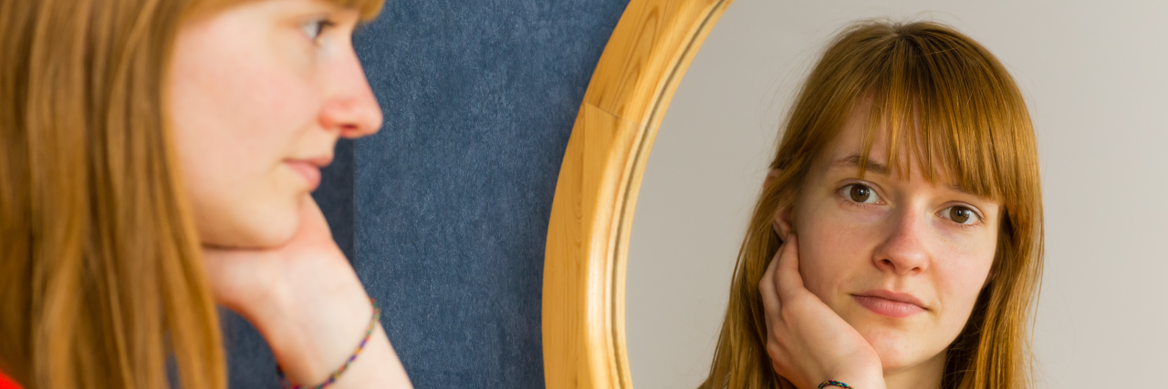 Feeling Alone as an Adult With Cerebral Palsy Red haired young woman looking at herself in the mirror.