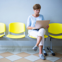 female patient sitting in a waiting room reading a report