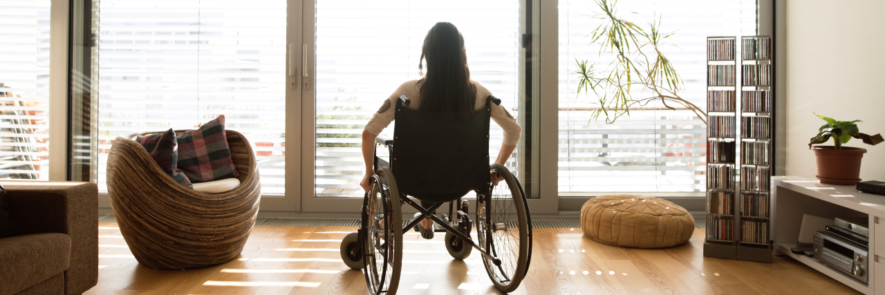 woman in her wheelchair at the window at home in her living room