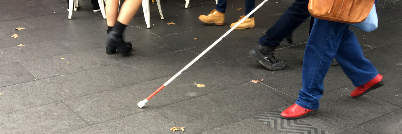 Going Beyond Shallow Inspiration When It Comes to Disability Visually impaired person walking down the street with a cane.