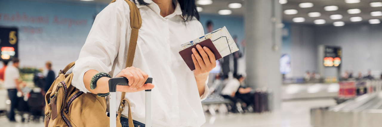 How Life Changes After Developing Heart Disease woman standing in the airport with her suitcase and passport