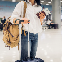 woman standing in the airport with her suitcase and passport