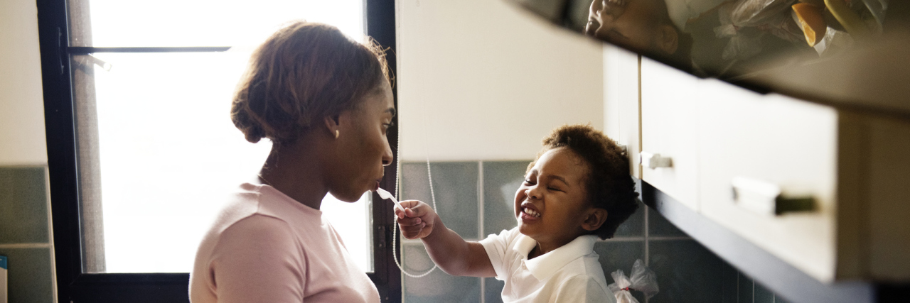 The 3 Psychological Needs of Parents of Kids With Disabilities Little boy feeding mom while she is making dinner.