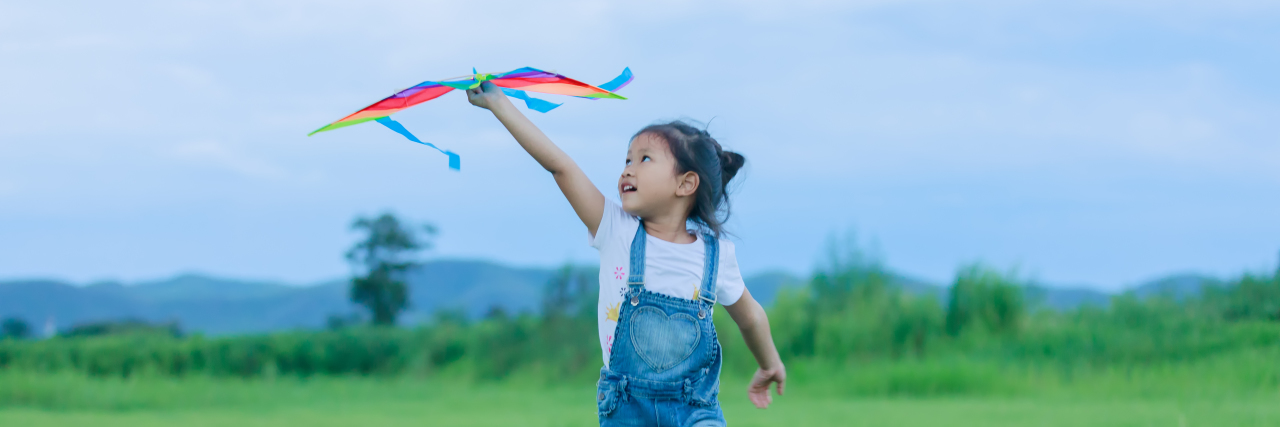 Asian girl with a kite running.