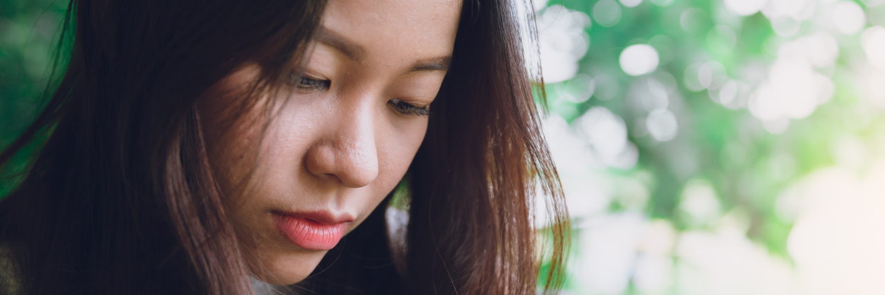 How Racism Has Affected Me as an Autistic Woman Asian woman looking down sadly.