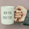 hand holding coffee mug that says new year fresh start