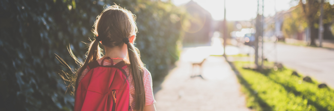 Why It's Difficult Growing Up With Crohn's Disease young girl with pigtails and a backpack walking to school