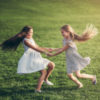 Two girls playing in a grassy field.