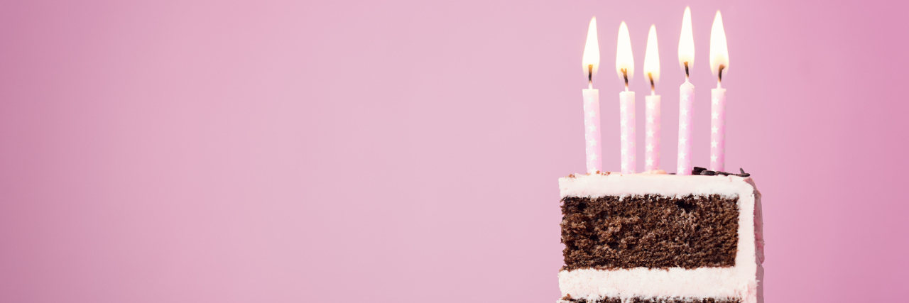 Chocolate birthday cake with pink frosting and candles