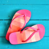 Pink flip-flop sandals on a bright blue background.