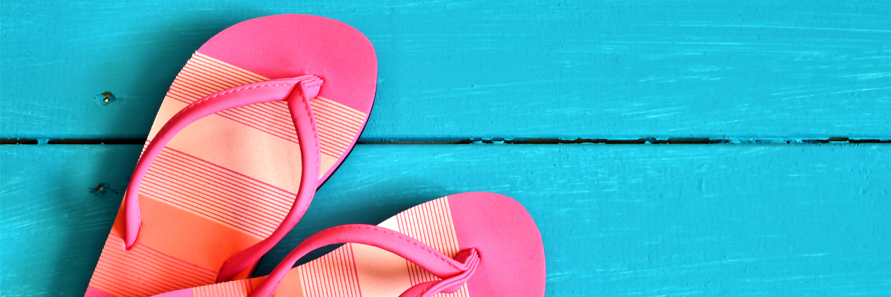 Pink flip-flop sandals on a bright blue background.