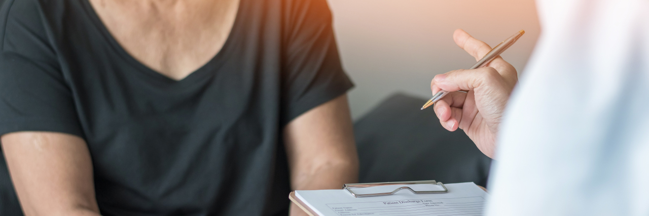 Doctor pointing at patient while taking notes.