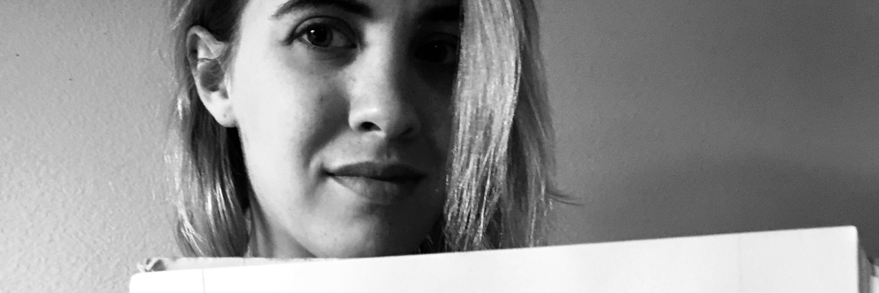 black and white photo of young woman holding paper saying I Am BPD with X through BPD replaced with "me"