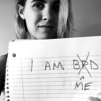 black and white photo of young woman holding paper saying I Am BPD with X through BPD replaced with "me"