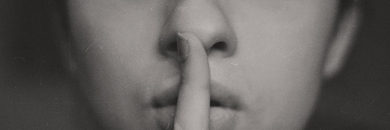 9 'White Lies' People With Anxiety Tell A woman putting her fingers to her lips. Text reads: 9 'white lies' people with anxiety tell