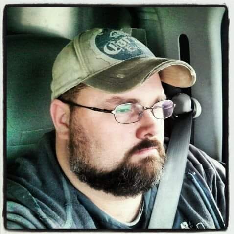 man in glasses looking out car windshield