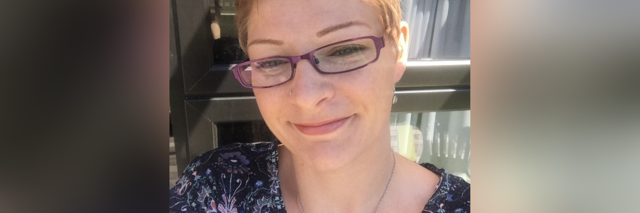 How Writing Helps Me Cope With Fibromyalgia and Other Health Issues selfie of the author wearing glasses and a blue shirt and standing in front of a window