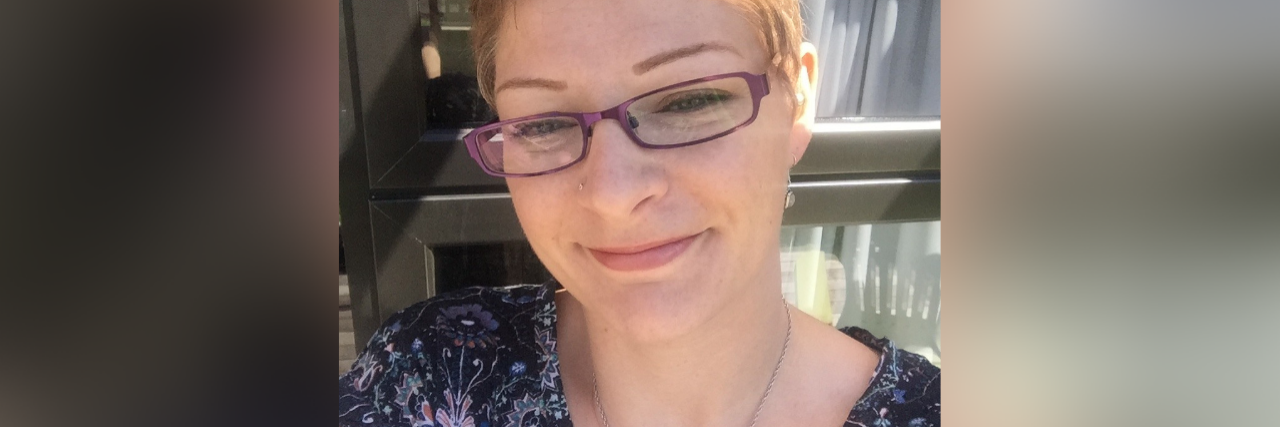 selfie of the author wearing glasses and a blue shirt and standing in front of a window