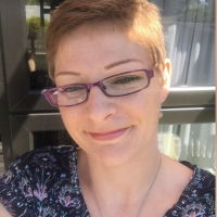 selfie of the author wearing glasses and a blue shirt and standing in front of a window