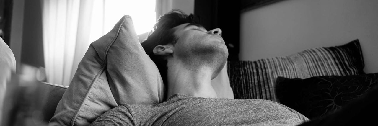 What It's Like to Be a Man in Your 20s With Chronic Illness black and white photo of man sleeping on the couch