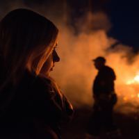 woman silhouetted and illuminated by flames looking at fire