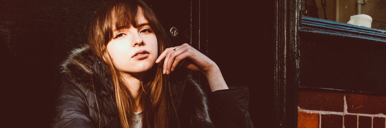 Please Don't Say These 8 Things to Someone Having a Panic Attack woman sitting on stoop looking at camera