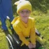 Little girl sitting on her wheelchair dressed in yellow costume.