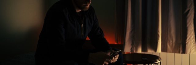 man in semi darkness holding phone about to make a call