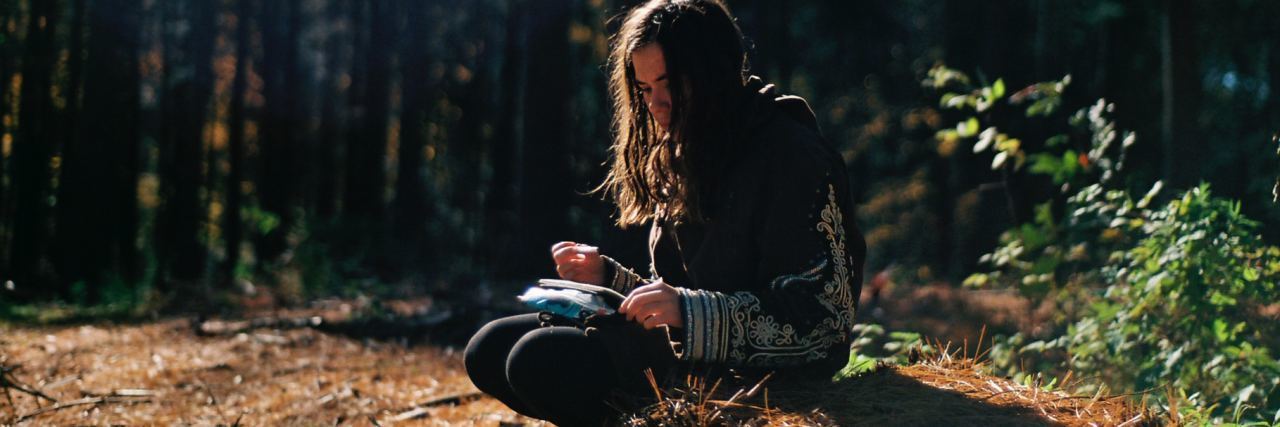 Depression, Anxiety and School Stress young woman sitting in woods writing with paper on knee
