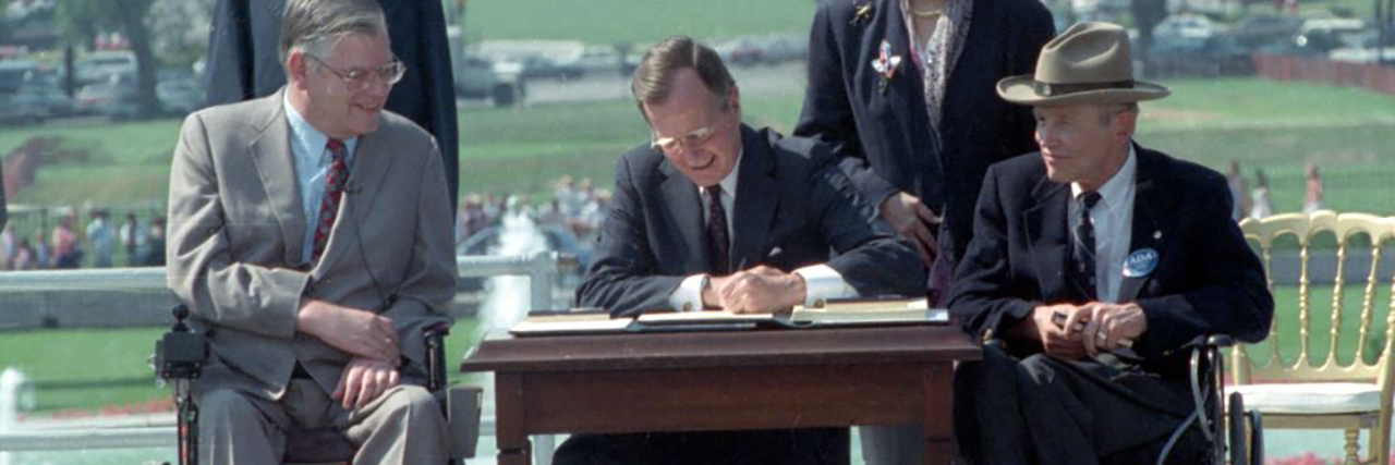 Honoring George H.W. Bush and the Americans With Disabilities Act President Bush signs the Americans with Disabilities Act on the South Lawn of the White House. Sharing the dais with the President and he signs the Act are (standing left to right): Rev. Harold Wilkie of Clairmont, California; Sandra Parrino, National Council on Disability; (seated left to right): Evan Kemp, Chairman, Equal Opportunity Commission; and Justin Dart, Presidential Commission on Employment of People with Disabilities. Mrs. Bush and Vice President Quayle participate in the Ceremony. 26 July 1990 Photo credit: George Bush Presidential Library and Museum