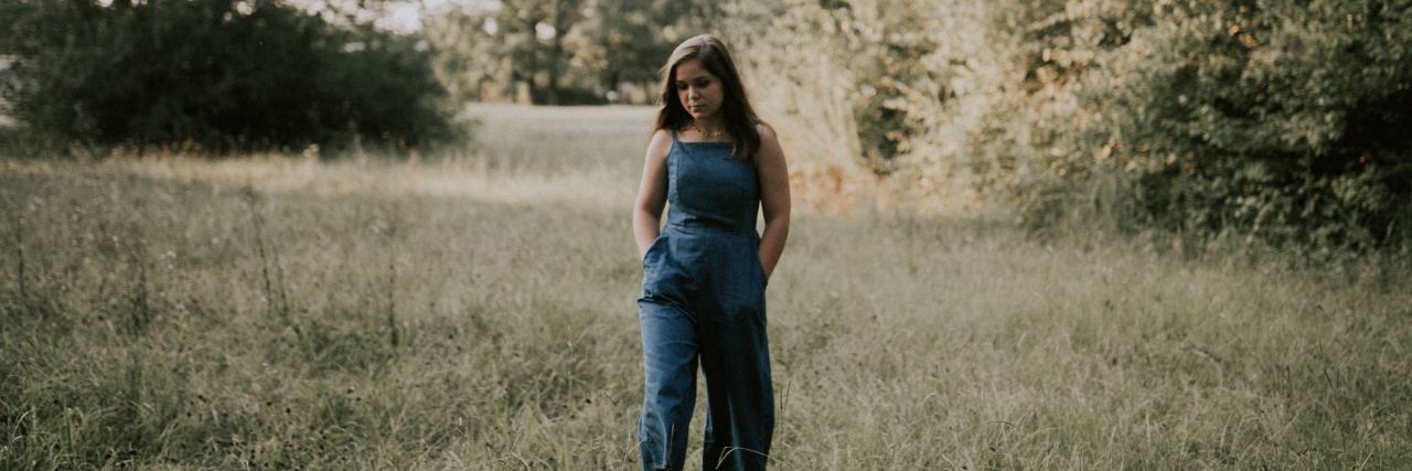 What to Know About Intermittent Explosive Disorder young woman standing in field with hands in pockets