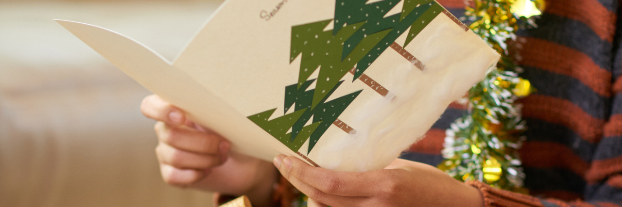 What a Holiday Letter by Someone With Chronic Illness Would Say young woman reading Christmas greeting card from her friend or relative