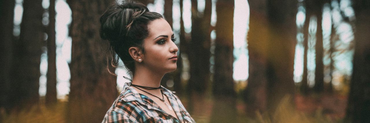The Parts of My Life I Would Reclaim From Anxiety woman standing with back to tree in forest looking determined