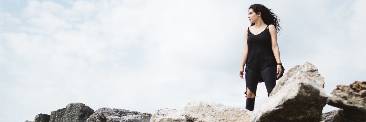 What to Know If You Think Depression Makes Me Weak dark haired woman standing in strong pose on rocks and silhouetted by sky