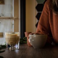 close up of woman sitting at table in sweater holding mug of coffee