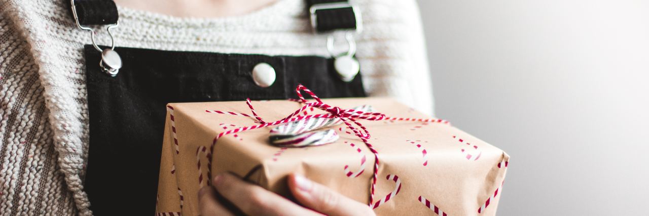 How to Support Someone Estranged From Family During the Holidays close up of woman holding wrapped christmas present close to her chest