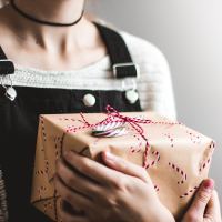 close up of woman holding wrapped christmas present close to her chest