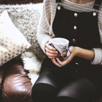 woman sitting on leather couch holding mug of tea or coffee