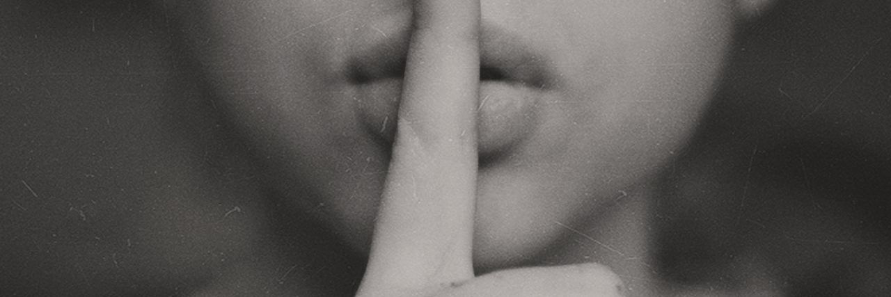 Things Better Left Unsaid to People With a Mental Illness black and white photo of woman with finger to lips in hush motion