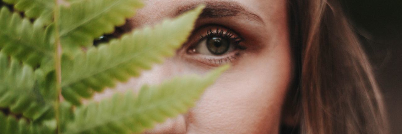 Friends Don’t Believe I Have BPD woman looking into camera and covering face with fern leaves
