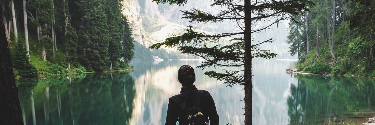A Therapist's Self-Improvement Advice for New Year's Resolutions person standing in mountains looking at reflection on water