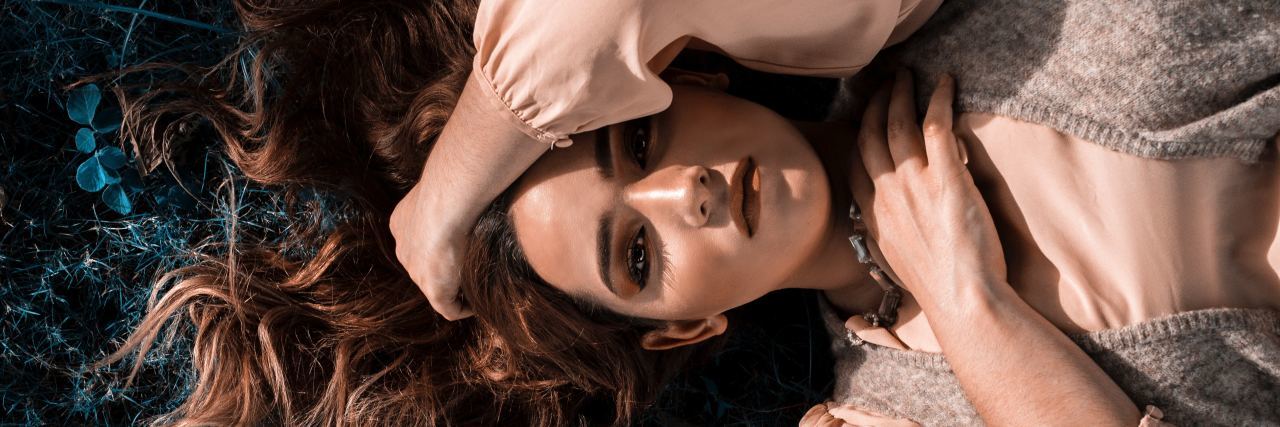 What You Need to Know About BPD and Dating overhead photo of woman lying on ground with hand in hair looking into camera with intensity