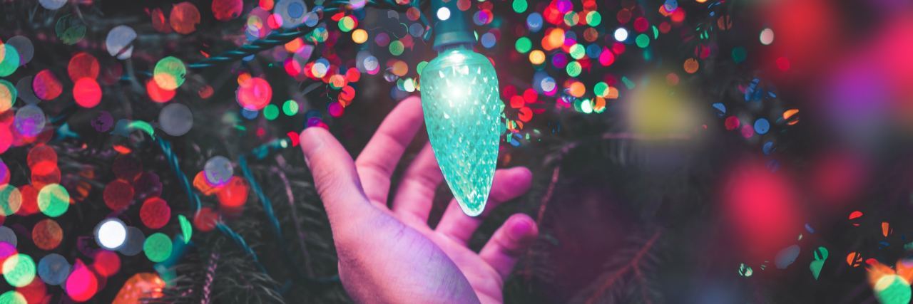 Advice for Staying in Addiction Recovery on Christmas A hand reaching towards Christmas lights
