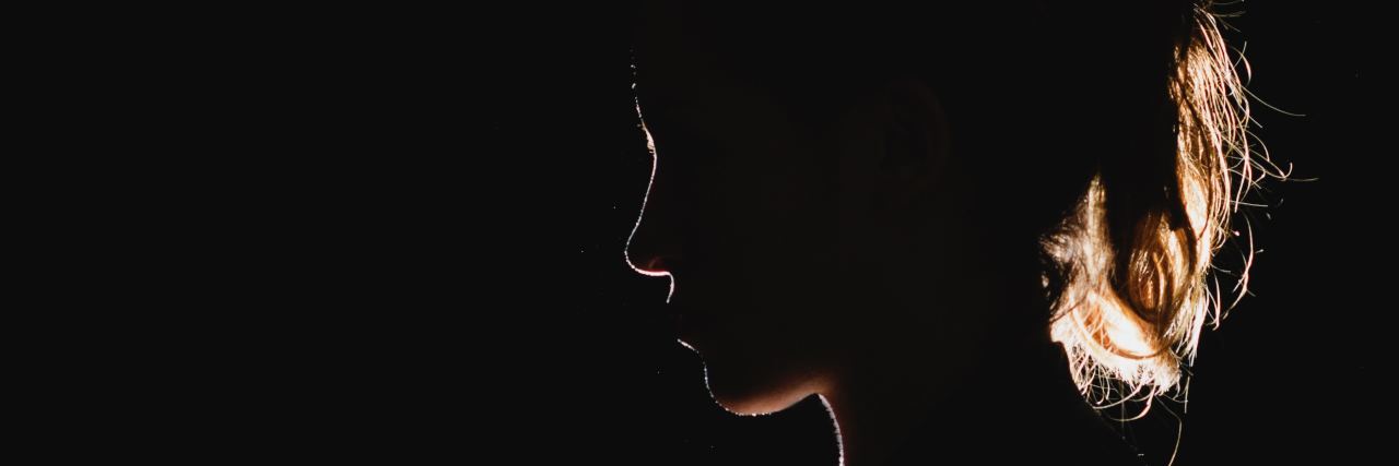 Reasons Your Suicidal Friend Won't Reach out for Help woman in darkness illuminated by light from behind and silhouetted