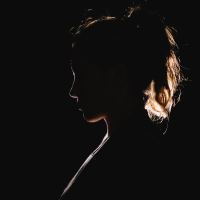 woman in darkness illuminated by light from behind and silhouetted
