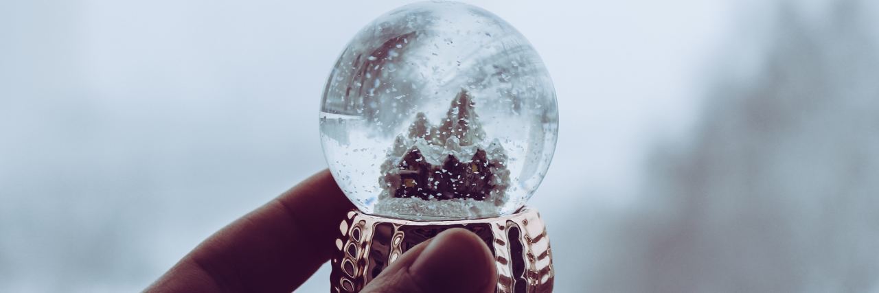 person holding snow globe against misty background