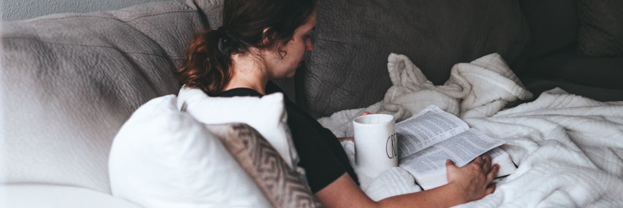 The Simple Self-Care Acronym for a Bad Mental Health Day photo of woman lying on sofa reading a book