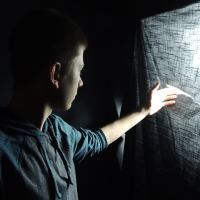young man reaching out hand to touch canvas and light