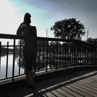 woman standing on boardwalk silhouetted in sunlight